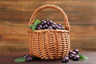 Photo of Basket and tasty acai berries on wooden table
