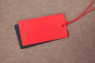 Photo of Red tag on brown garment, top view. Space for text