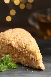 Photo of Piece of delicious Napoleon cake with mint on gray table, closeup