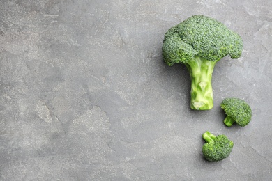 Flat lay composition of fresh green broccoli on grey stone table, space for text