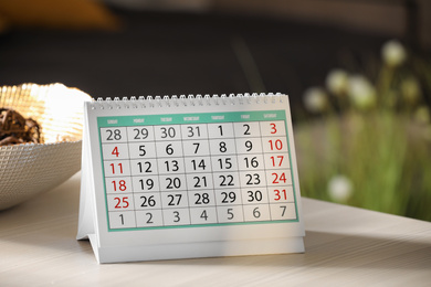 Photo of Paper calendar on light wooden table indoors