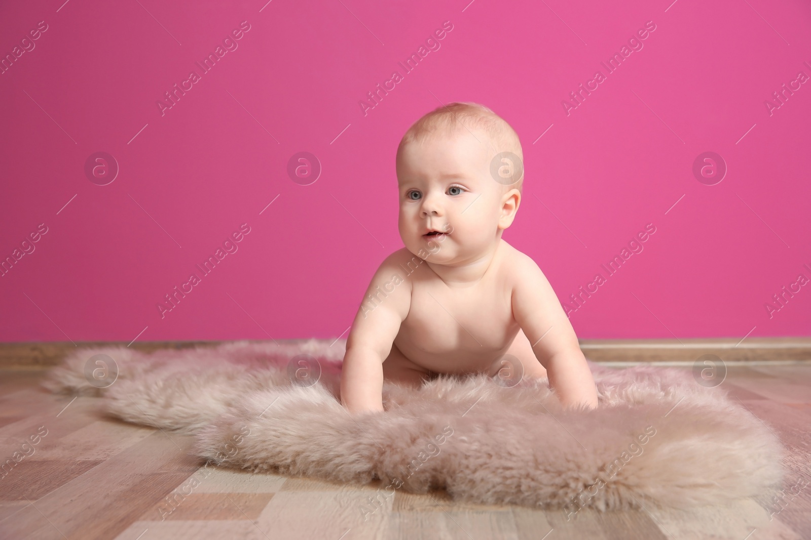 Photo of Cute little baby on fluffy rug near color wall