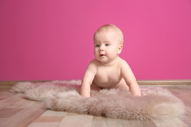 Photo of Cute little baby on fluffy rug near color wall