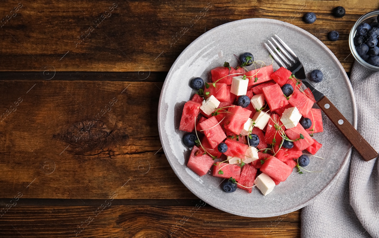 Photo of Delicious salad with watermelon, blueberries and feta cheese on wooden table, flat lay. Space for text