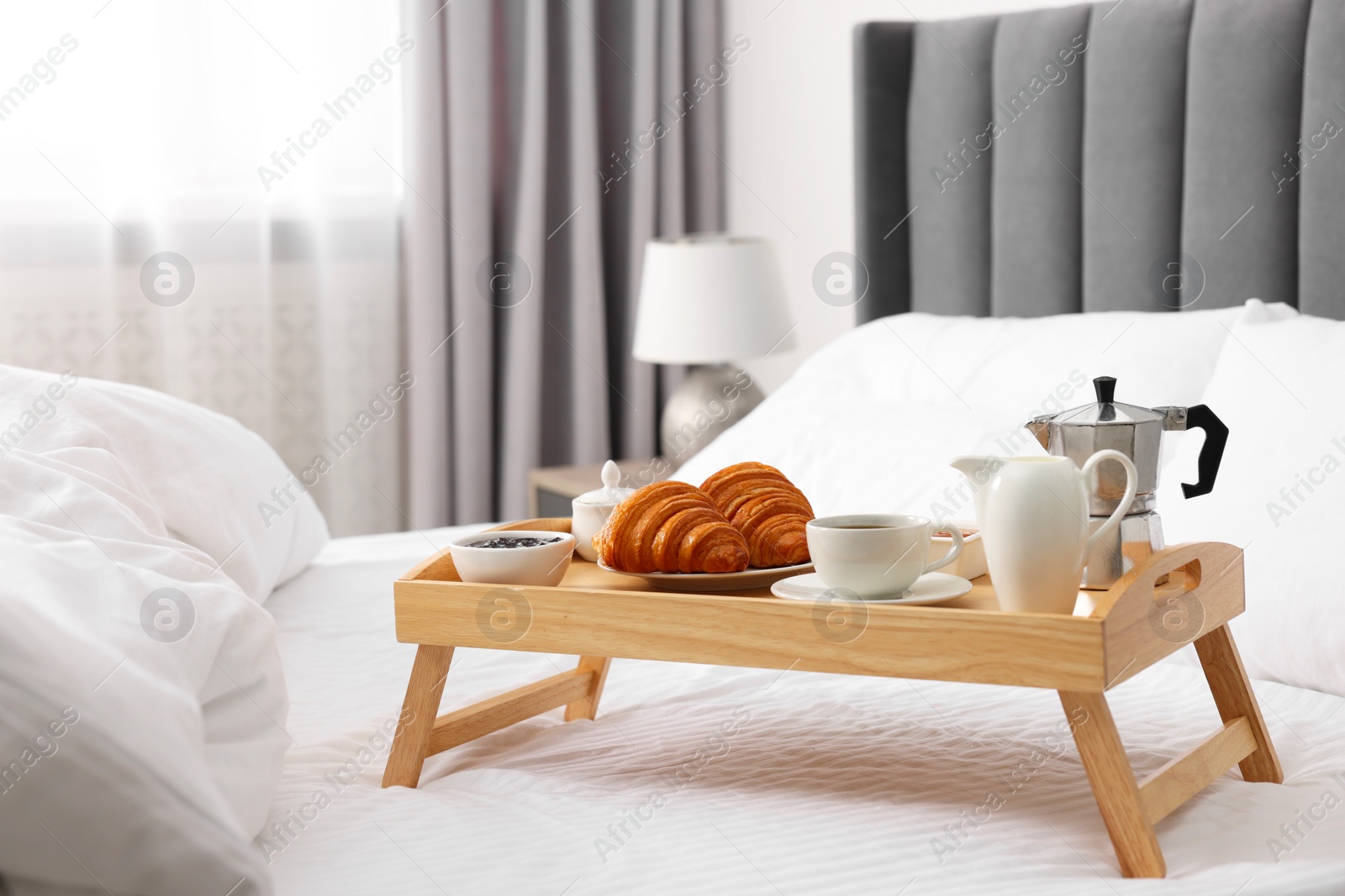 Wooden tray with tasty breakfast on bed at home Photo of Wooden tray with tasty breakfast on bed at home