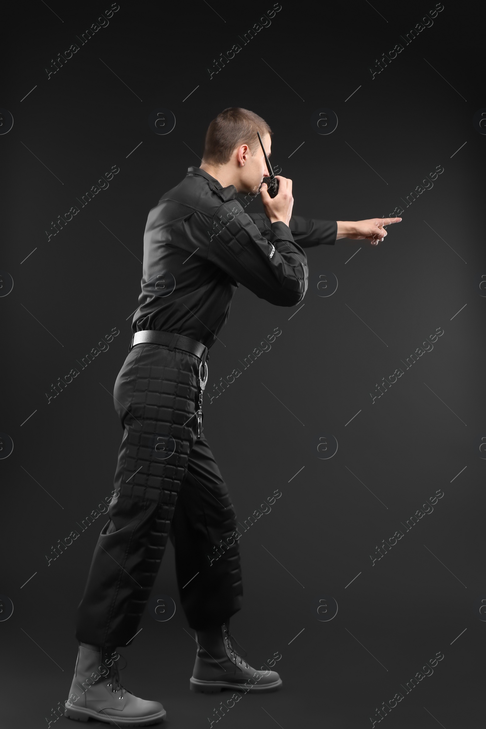 Photo of Male security guard using portable radio transmitter on dark background