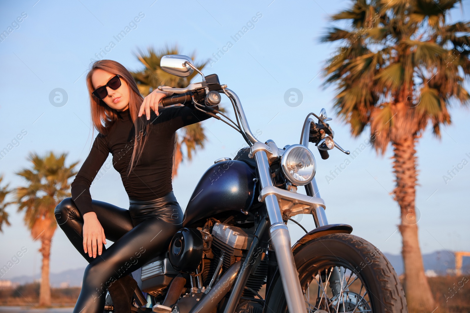 Photo of Beautiful young woman sitting on motorcycle outdoors