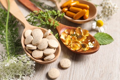 Different pills, herbs and flowers on wooden table, closeup. Dietary supplements