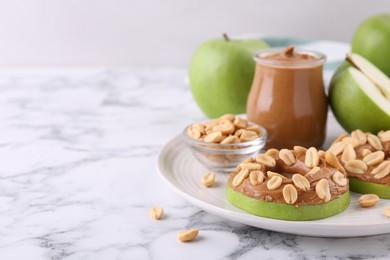 Photo of Fresh green apples with peanut butter and nuts on white marble table, closeup. Space for text