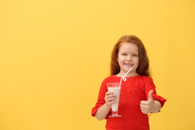 Photo of Little girl with glass of delicious milk shake on color background