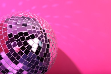 Photo of Shiny disco ball on pink background, closeup. Space for text