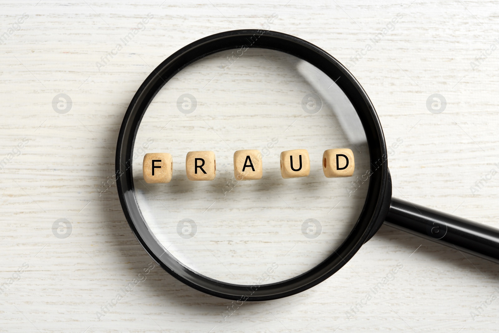 Photo of Word Fraud of cubes with letters and magnifying glass on white wooden background, flat lay
