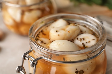 Photo of Preserved garlic in glass jar on table, closeup