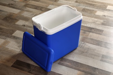 Open blue plastic cool box on wooden floor