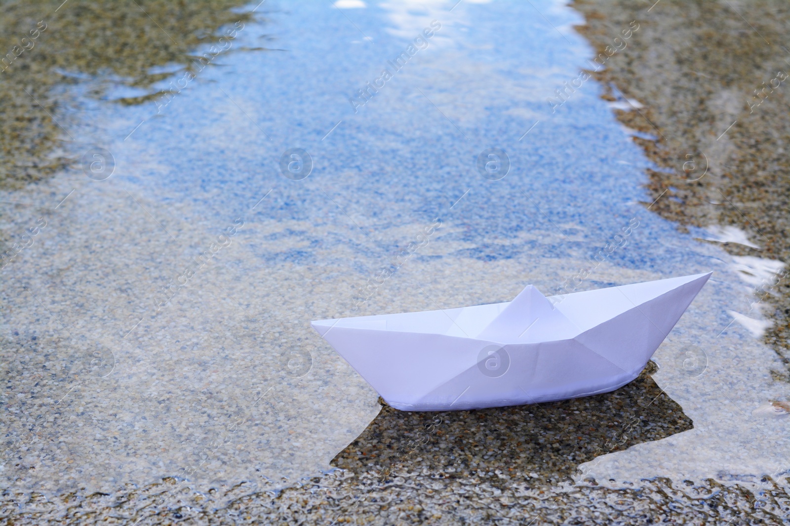 Photo of Beautiful white paper boat on water outdoors, space for text