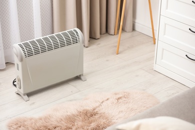Photo of Modern electric heater on floor at home