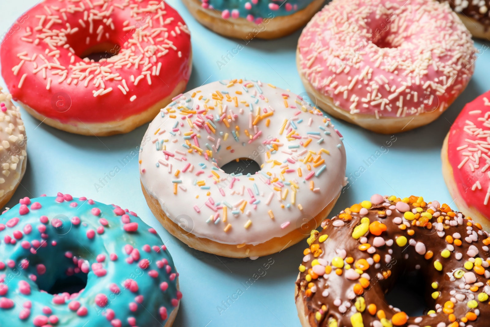 Photo of Delicious glazed doughnuts with sprinkles on color background