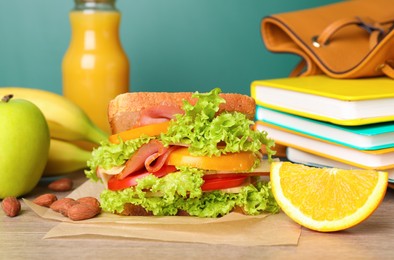 Photo of Tasty healthy food and different stationery on wooden table near green chalkboard, closeup. School lunch