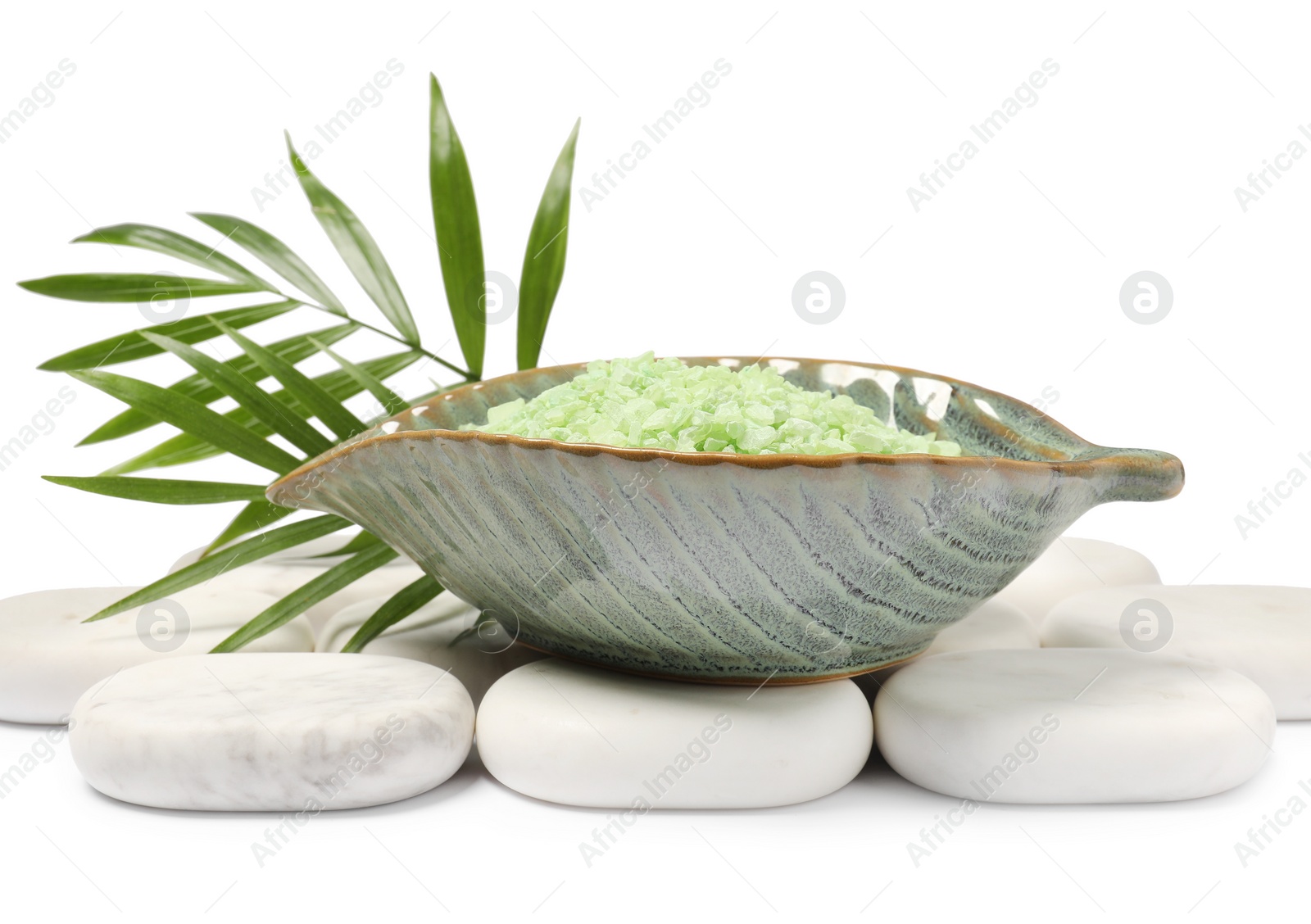 Photo of Green sea salt in bowl, spa stones and palm leaves isolated on white