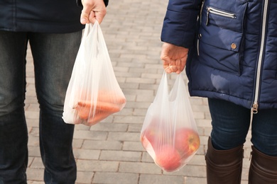 Photo of People carrying plastic bags with products outdoors, closeup