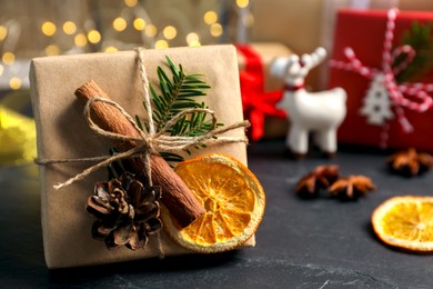 Beautiful gift box with Christmas decorations on black table, closeup. Space for text