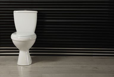 Photo of Toilet bowl near dark wall indoors. Space for text