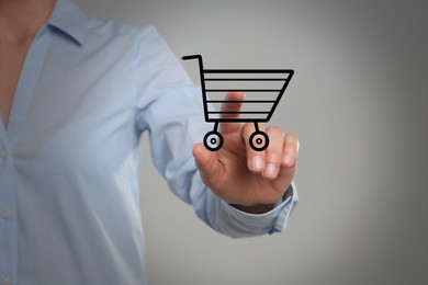 Woman demonstrating virtual image of shopping cart on light grey background, closeup