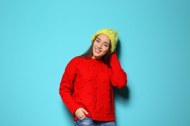 Photo of Young woman in warm sweater and hat on color background. Celebrating Christmas