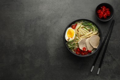 Delicious ramen with meat in bowl served on grey textured table, flat lay. Space for text. Noodle soup