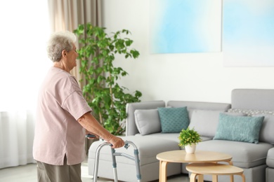 Elderly woman using walking frame at home