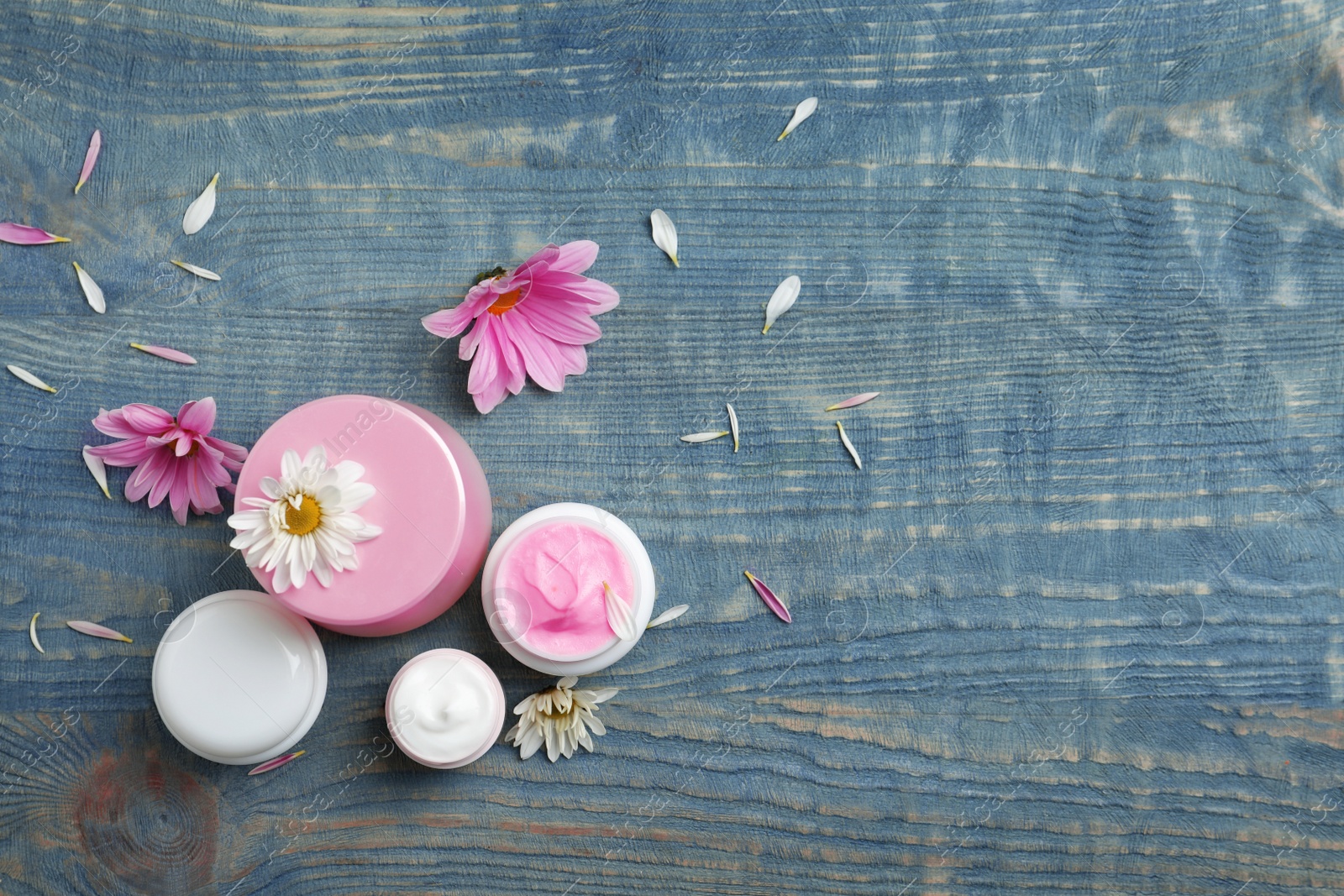 Photo of Composition with body cream in jars on wooden background, top view