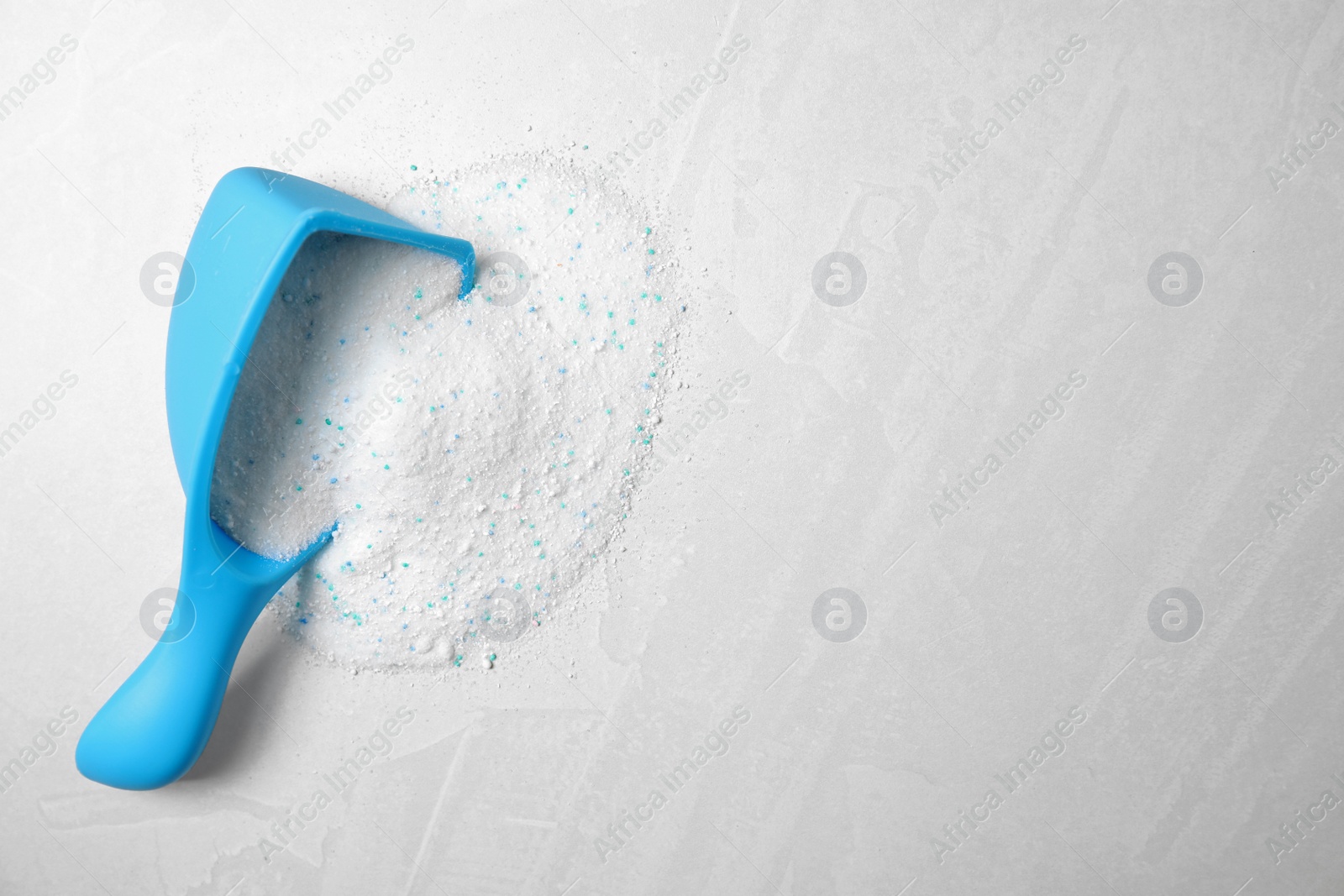 Photo of Measuring scoop with laundry detergent on light background, top view. Space for text