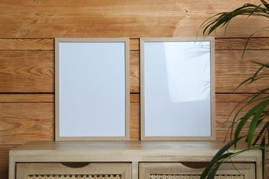 Empty frames on table near wooden wall. Mockup for design