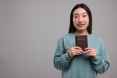 Immigration. Happy woman with passport on grey background, space for text