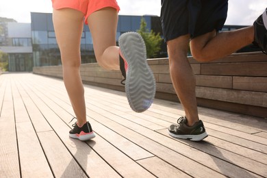 Photo of Healthy lifestyle. Couple running outdoors on sunny day, closeup