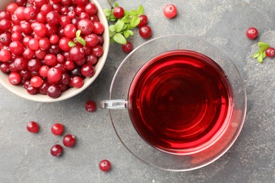 Photo of Tasty hot cranberry tea in glass cup and fresh berries on light grey textured table