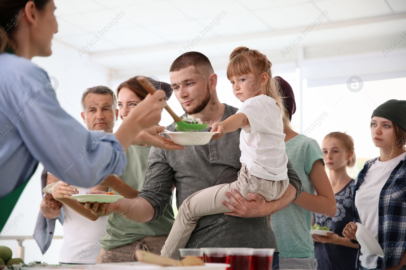 Photo of Volunteers serving food for poor people indoors