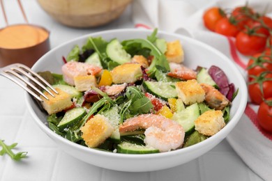 Photo of Delicious salad with croutons, cucumber and shrimp served on white tiled table, closeup