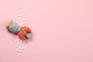 Endocrinology, Pills and model of thyroid gland on pink background, top view. Space for text