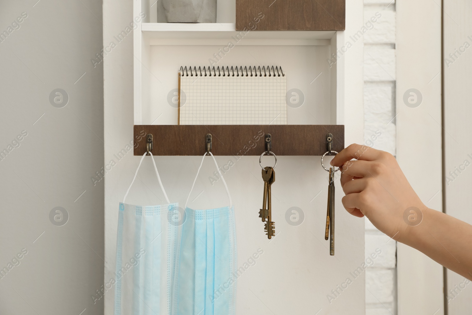 Photo of Woman taking keys from hanger in hallway, closeup