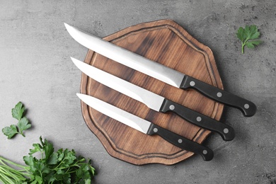 Flat lay composition with cutting board and knives on grey background