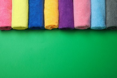 Photo of Many colorful microfiber cloths on green background, flat lay. Space for text