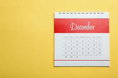 December calendar on yellow background, top view. Space for text