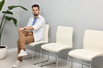 Photo of Man sitting on chair and waiting for appointment indoors