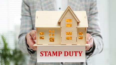 Image of Stamp duty. Woman holding wooden house model, closeup