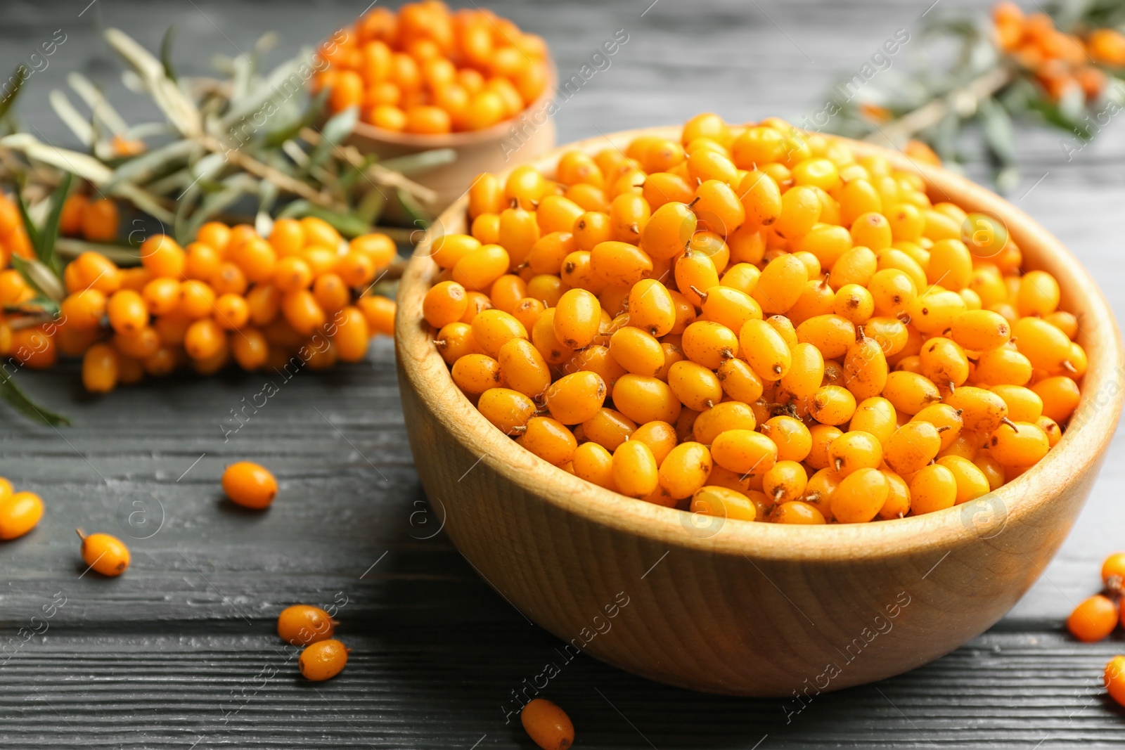 Photo of Ripe sea buckthorn berries on grey wooden table, closeup