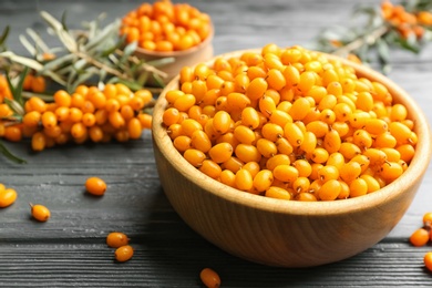 Ripe sea buckthorn berries on grey wooden table, closeup