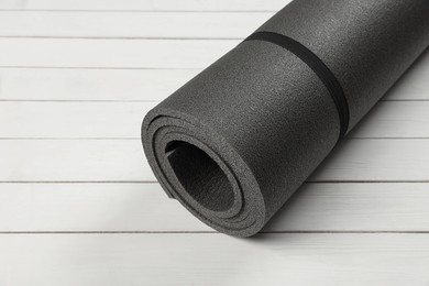 Photo of Yoga mat on white wooden floor. Space for text