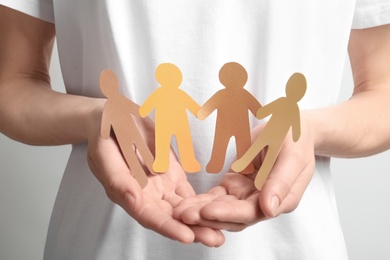 Photo of Young woman holding paper people, closeup. Unity concept