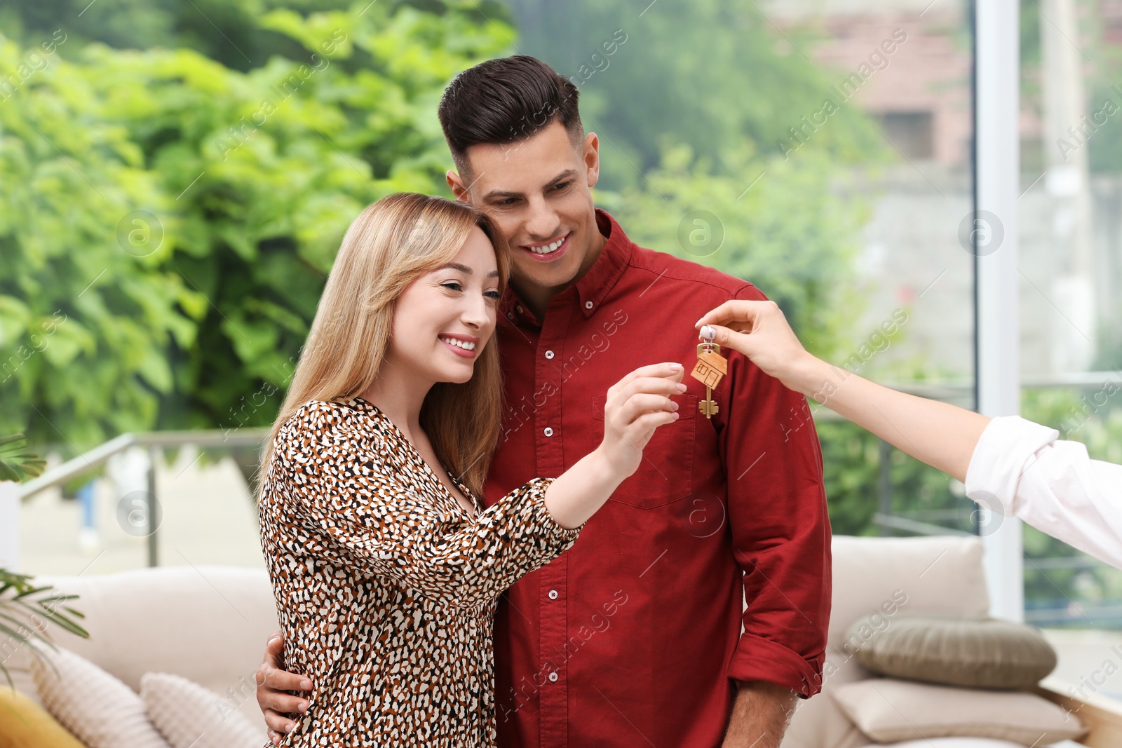 Photo of Real estate agent giving house key to couple indoors